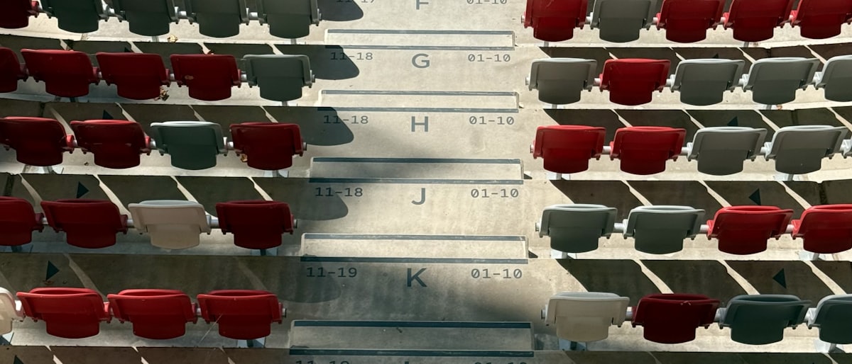 Rows of stadium seats seen from above, each row marked with a letter and seat numbers.